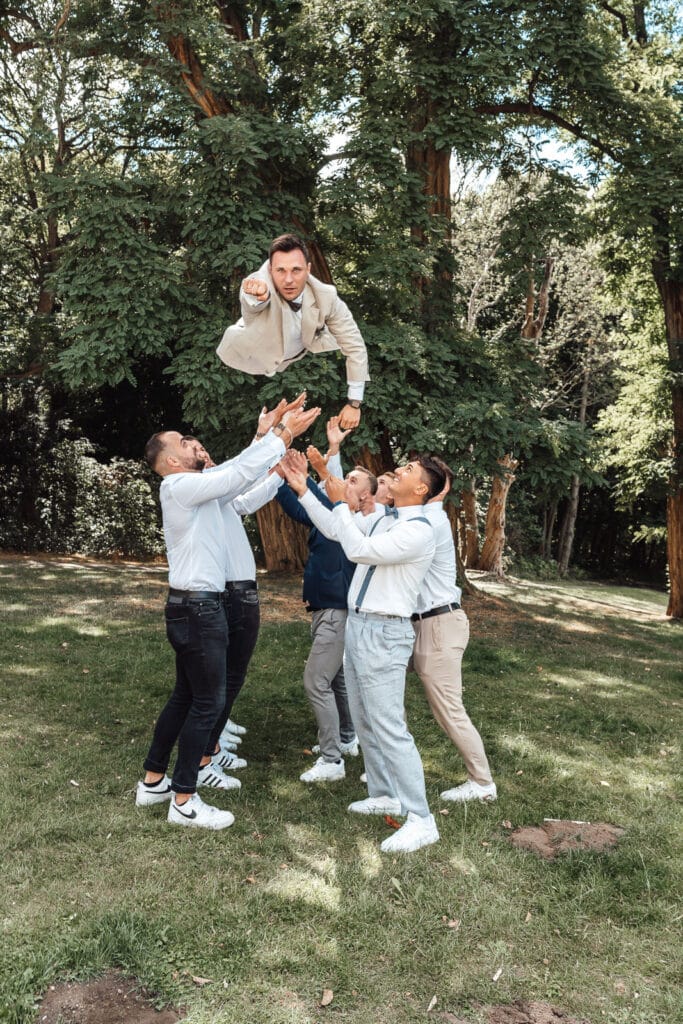 Hochzeitsfotograf aus Wolfsburg fotografiert am Schloss Richmond, wie Freunde den Br&auml;utigam in die Luft werfen