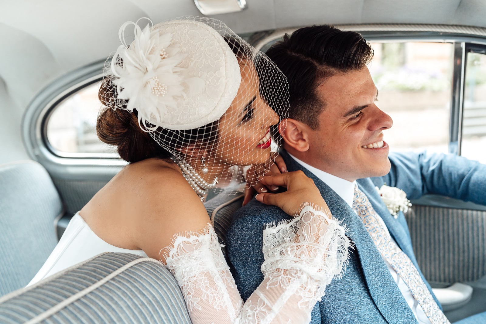 Brautpaar sitzt in einem alten Mercedes und umarmt sich, Braut trägt einen Hut im 1920er Stil