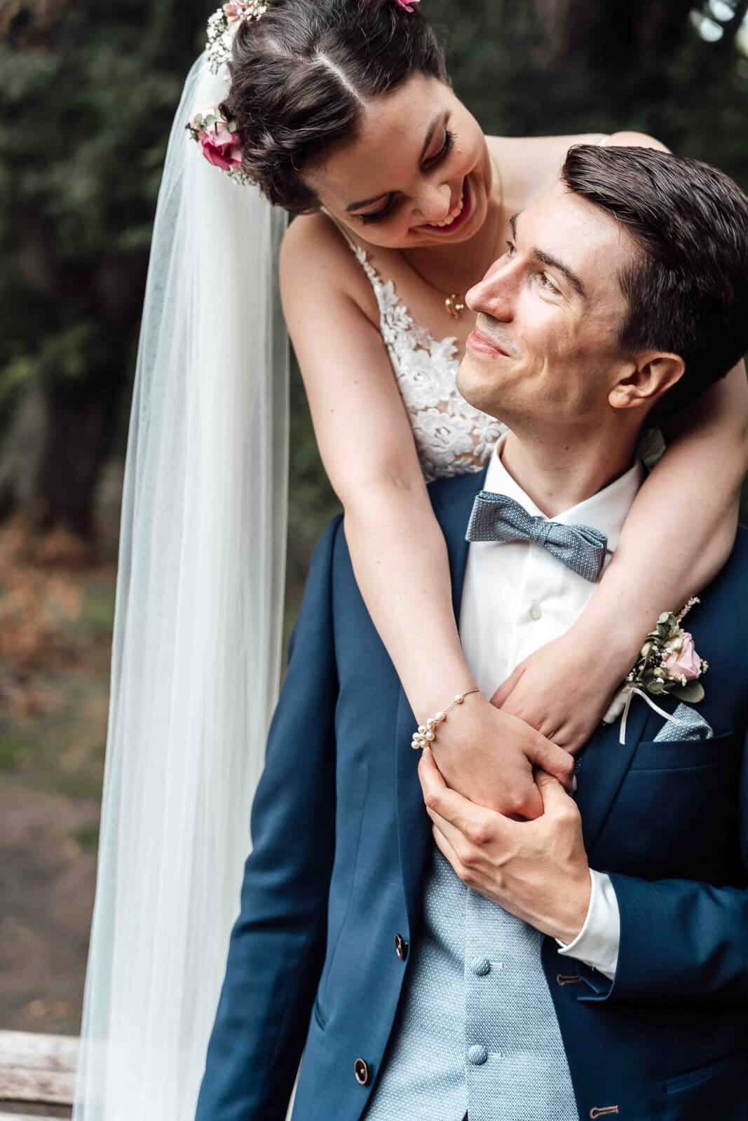 Brautpaarshooting im Schlosspark Braunschweig: Braut umarmt den Bräutigam, natürlicher und emotionaler Moment im Grünen