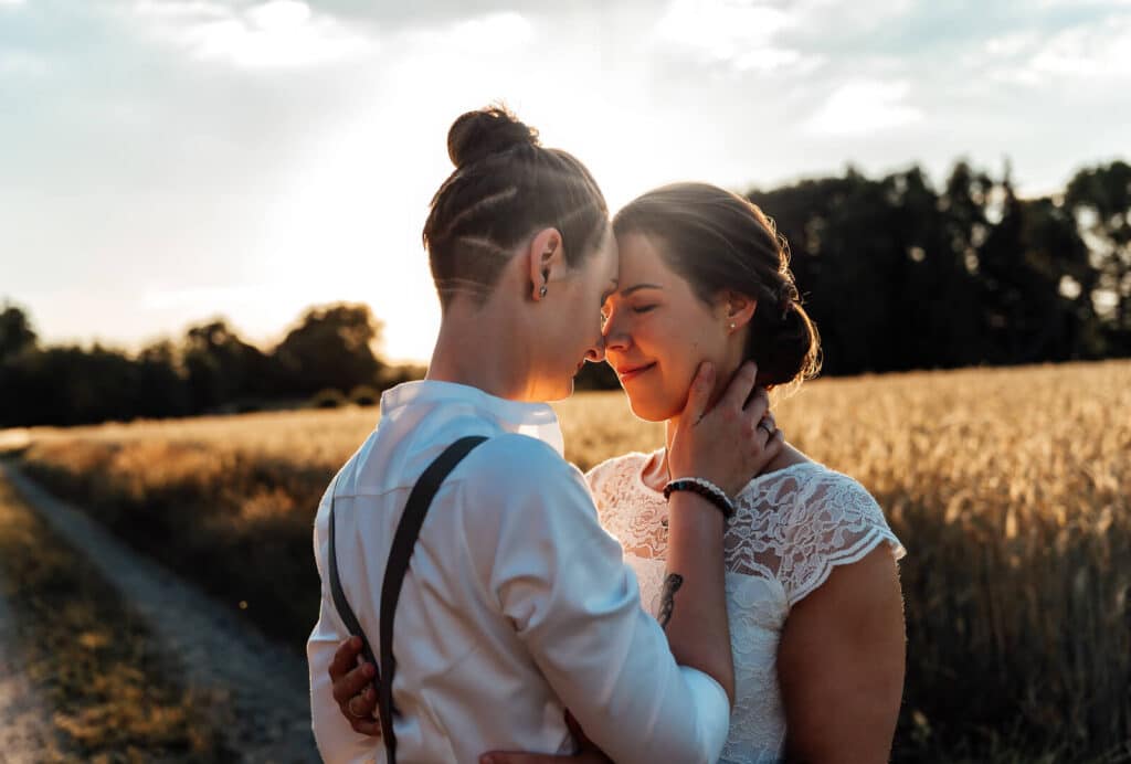 Sinnliches Sonnenuntergangshooting in Braunschweig vor einer Weide: Paar steht Stirn an Stirn im warmen Abendlicht