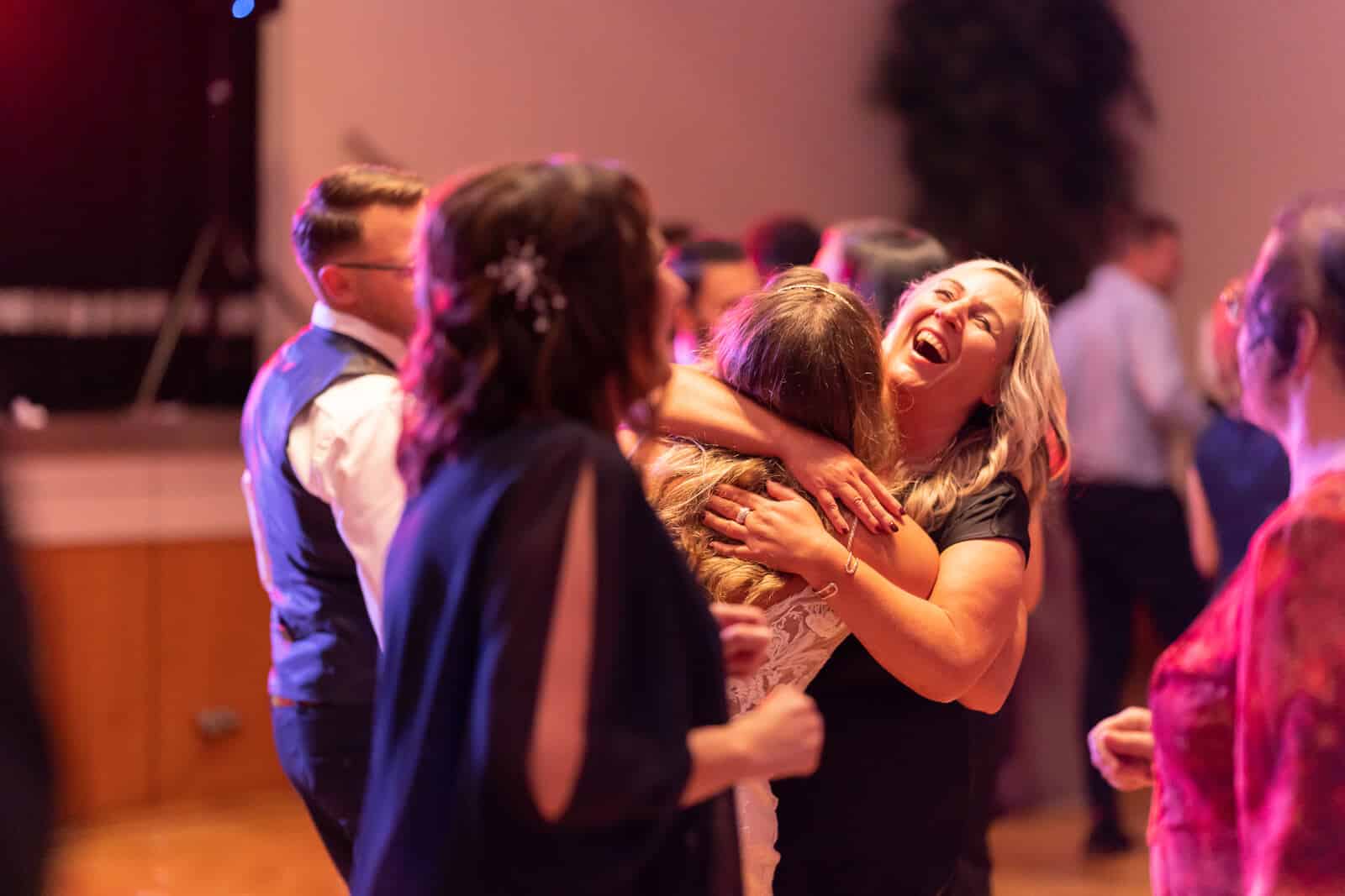 Ausgelassene Hochzeitsparty: Gäste umarmen sich lachend auf der Tanzfläche