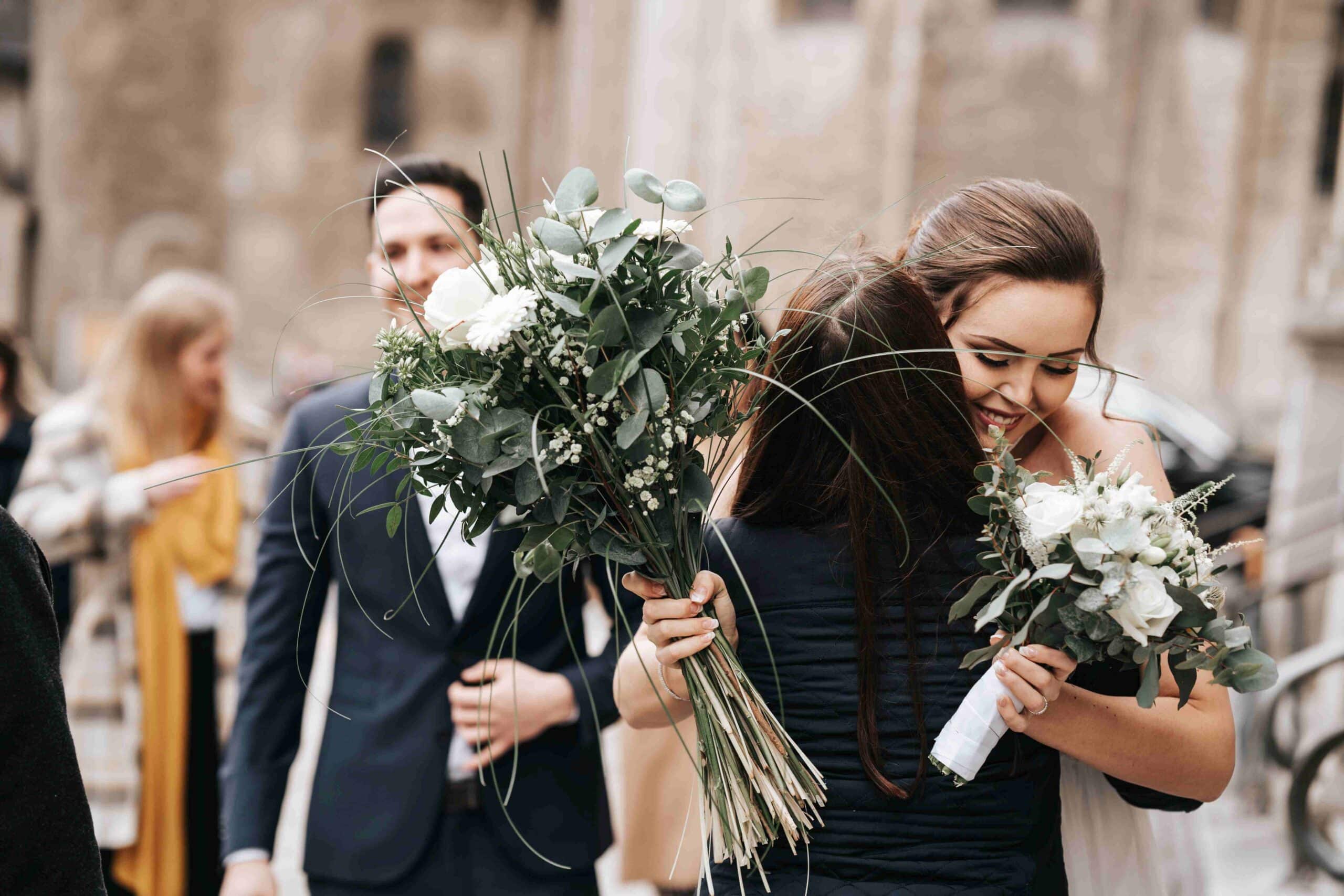 Braut umarmt ihre Mutter und hält einen Blumenstrauß in der Hand, emotionaler Hochzeitsmoment