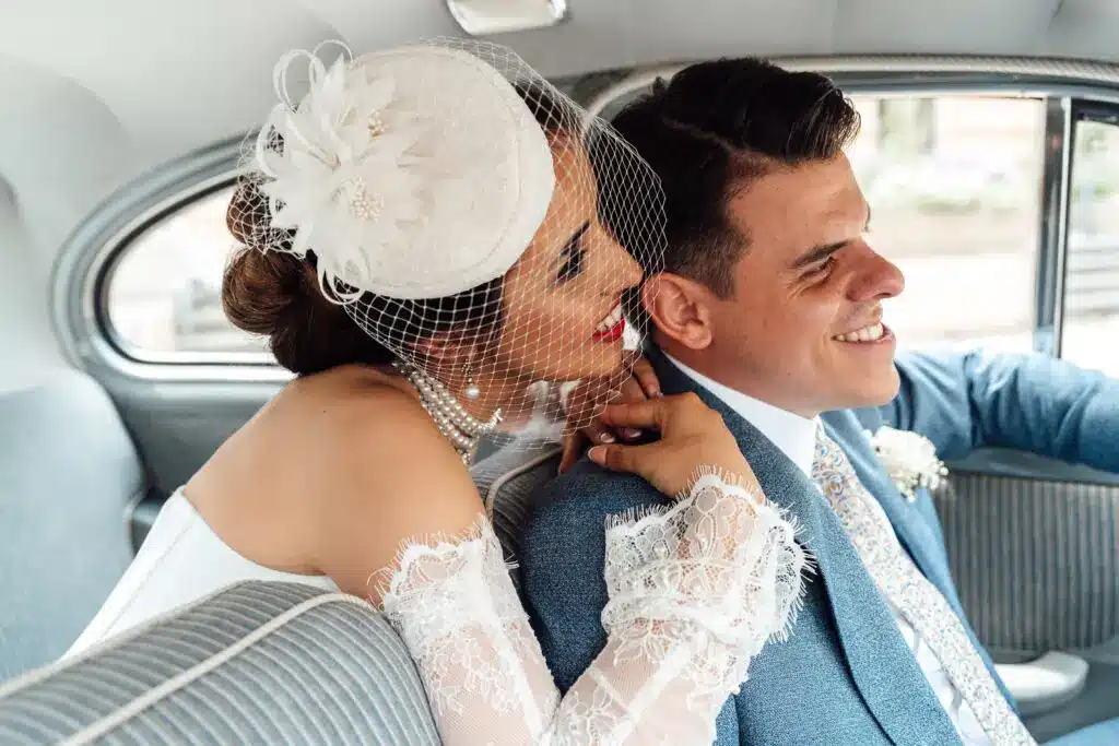 Brautpaar sitzt in einem alten Mercedes und umarmt sich, Braut trägt einen Hut im 1920er Stil