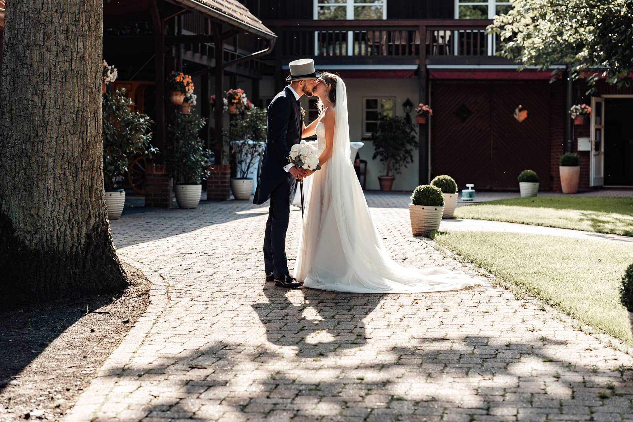 Brautpaar küsst sich, Bräutigam trägt einen Zylinder, romantischer Vintage-Hochzeitsmoment
