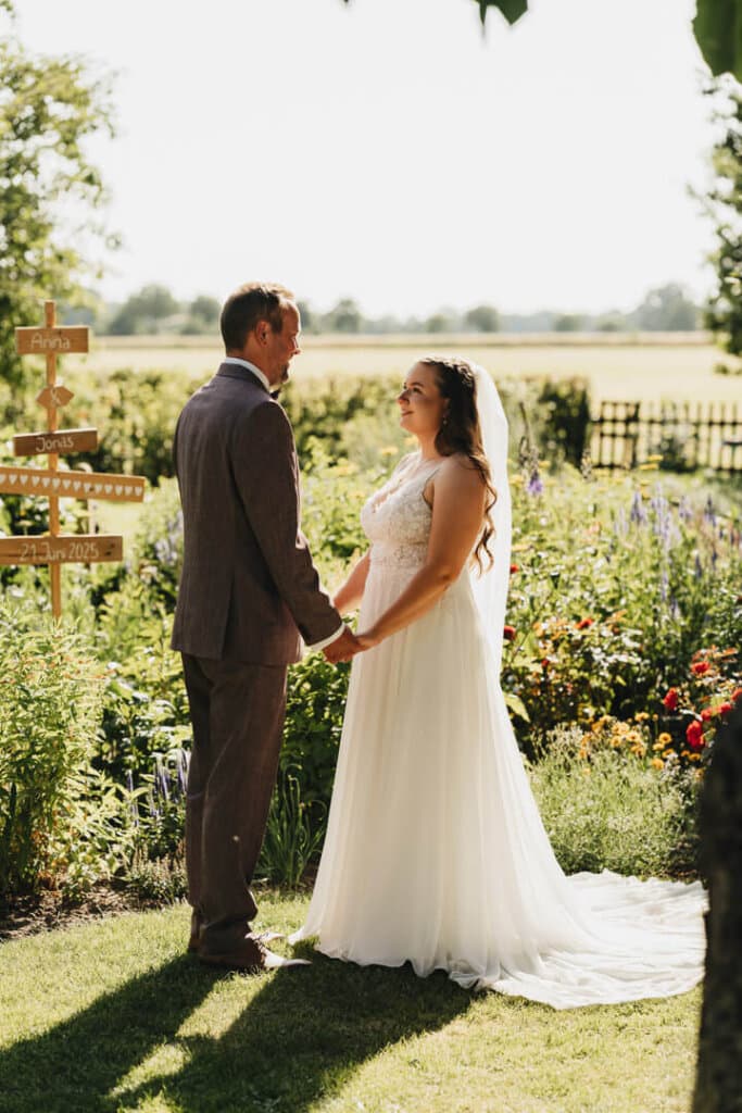 Brautpaarshooting im Garten in Adensbüttel bei Sonnenuntergang: Brautpaar hält sich die Hände und schaut sich in die Augen