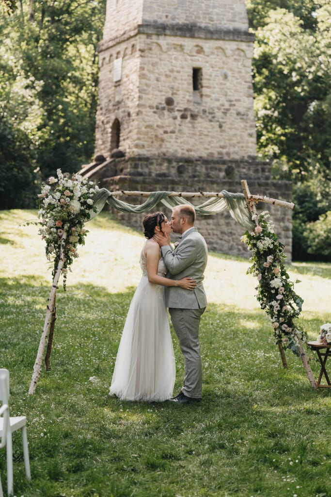 Brautpaarshooting in Heese 5: Brautpaar küsst sich unter einem Torbogen, romantischer Moment in moderner Kulisse