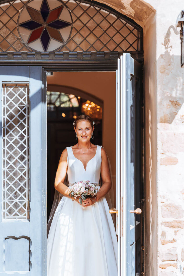 Brautpaarshooting am Schloss Destedt auf der Wiese: Brautpaar hält sich die Hände und lächelt sich an, natürlicher Moment