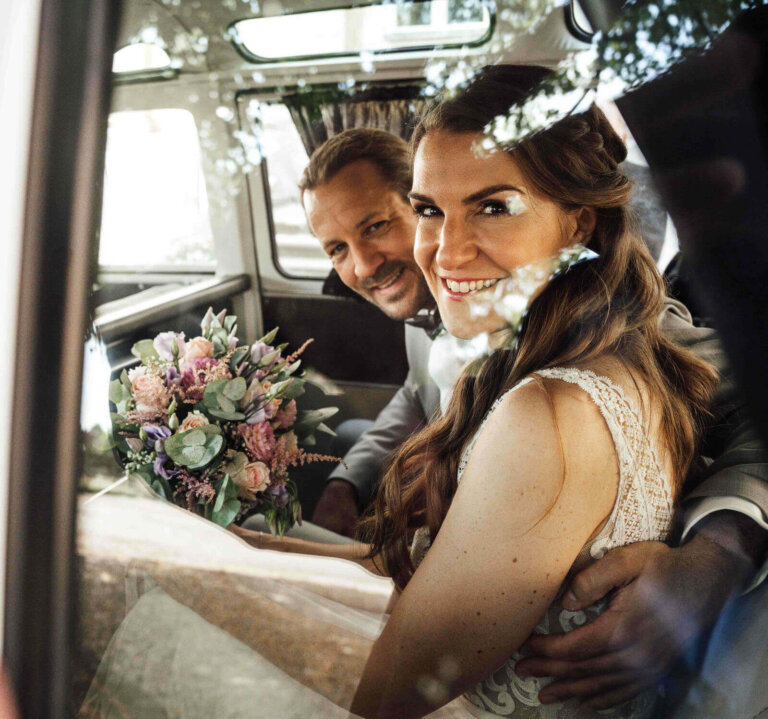 Brautpaarshooting am Schloss Destedt: Brautpaar sitzt in einem hellblauen VW Bulli und schaut in die Kamera
