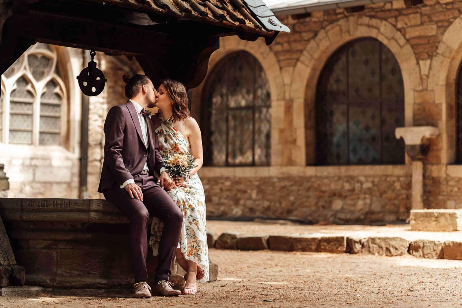 Brautpaarshooting in der Stadt Braunschweig: Bräutigam küsst die Braut am Brunnen, urbaner und romantischer Moment