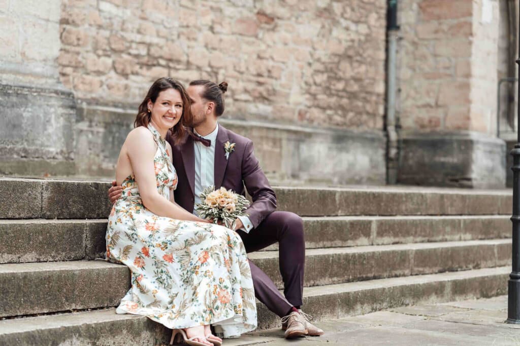 Brautpaarshooting in der Stadt Braunschweig: Brautpaar sitzt an einer Treppe, urbaner und natürlicher Moment