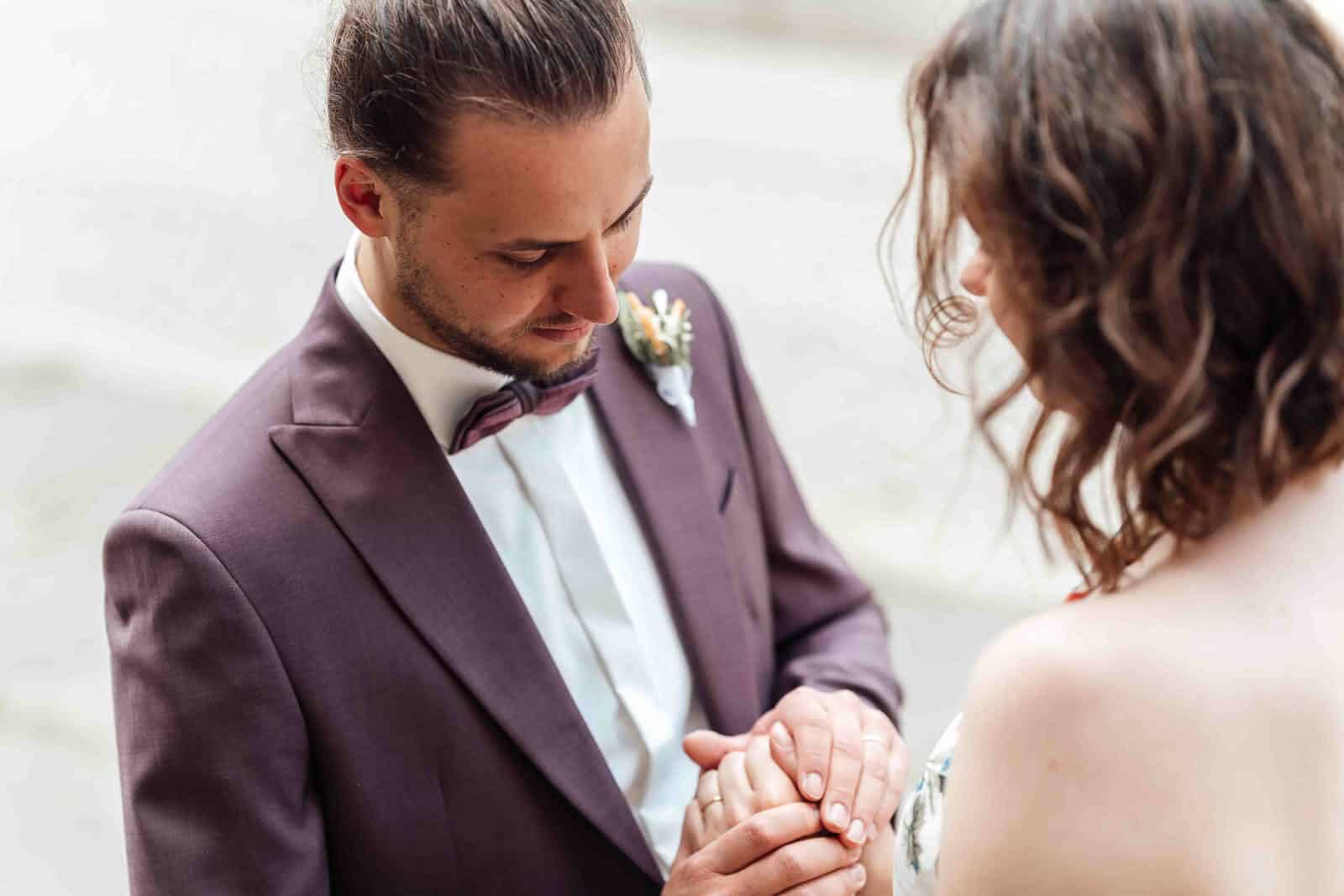 Brautpaarshooting in der Stadt Braunschweig: Bräutigam hält die Hände seiner Frau, natürlicher und intimer Moment in urbaner Kulisse