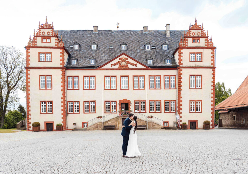 Brautpaarshooting am Schloss Salder in Salzgitter: Brautpaar umarmt sich, Schloss im Hintergrund, romantischer Moment