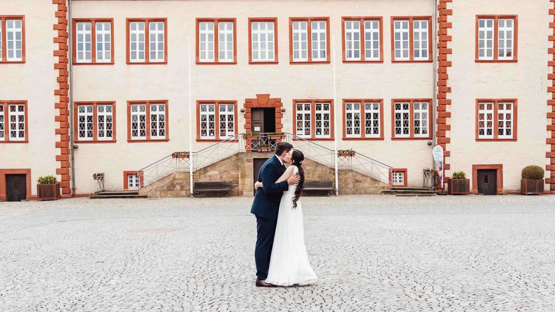 Brautpaarshooting am Schloss Salder in Salzgitter: Brautpaar umarmt sich, Schloss im Hintergrund, romantischer Moment