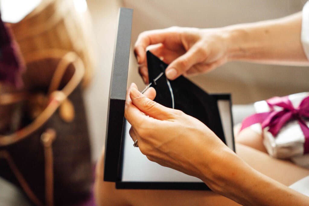 Braut holt beim Getting Ready eine Halskette aus einer Schatulle, Detailaufnahme mit ruhiger Stimmung
