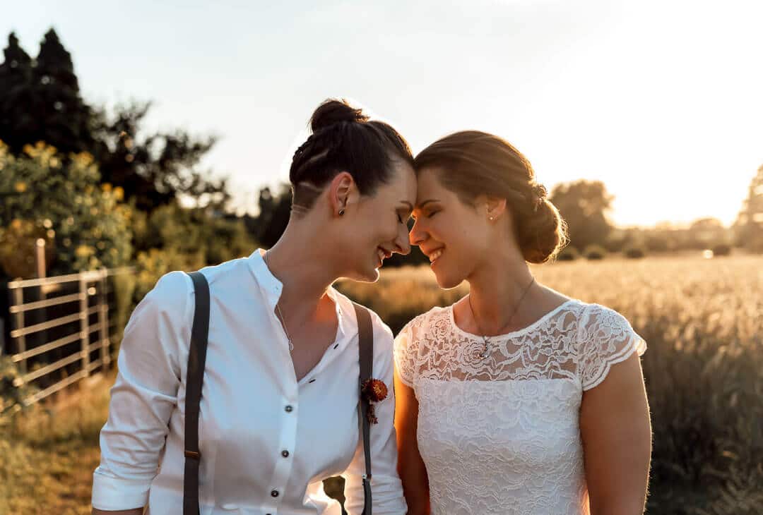 Sinnliches Sonnenuntergangshooting in Braunschweig vor einer Weide: Paar steht Stirn an Stirn im warmen Abendlicht