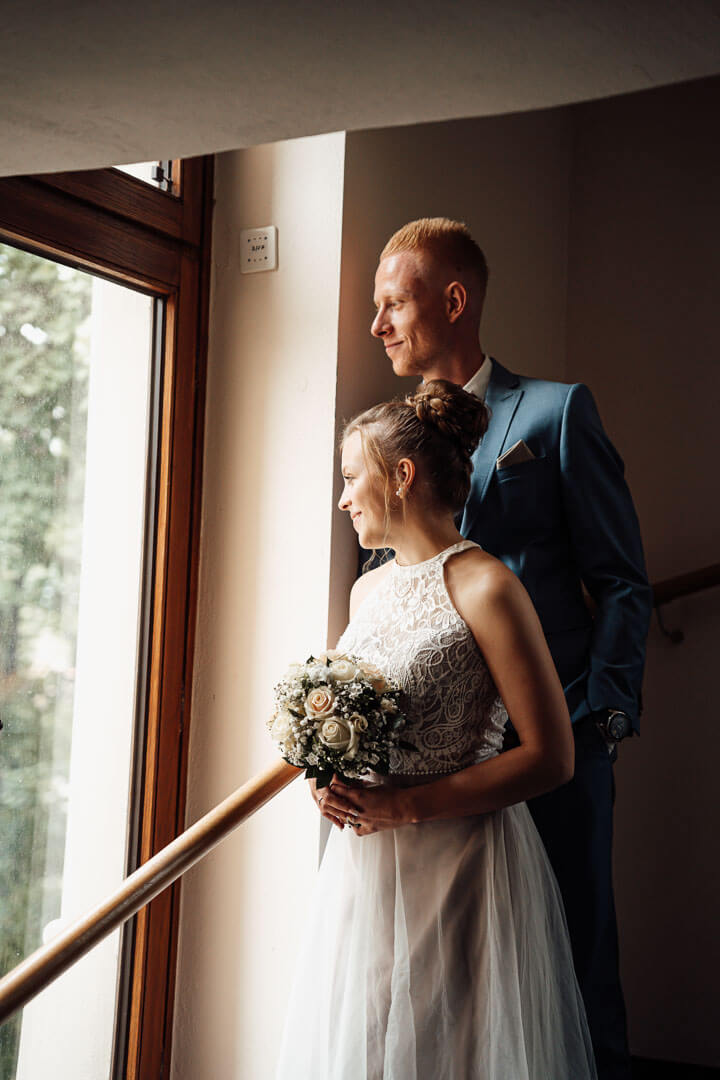 Brautpaarshooting an der Villa Seeliger in Wolfenbüttel: Brautpaar steht am Fenster, intimer Moment in stilvoller Kulisse