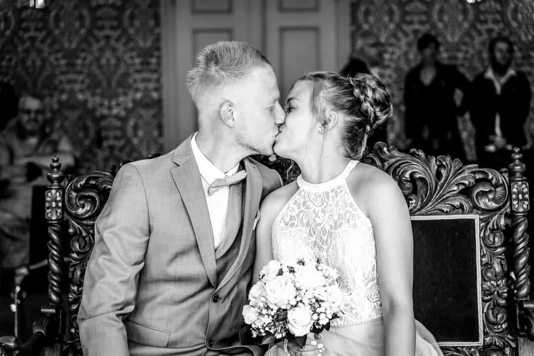 Schwarz-Weiß Aufnahme im Standesamt Villa Seeliger: Brautpaar küsst sich am Altar nach dem Ja-Wort