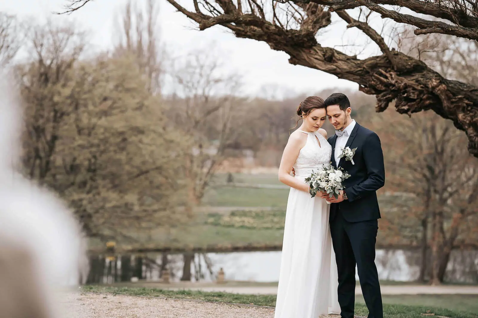 Brautpaar unter Baum am Schloss Richmond Hannover mit Brautstrauß in den Händen
