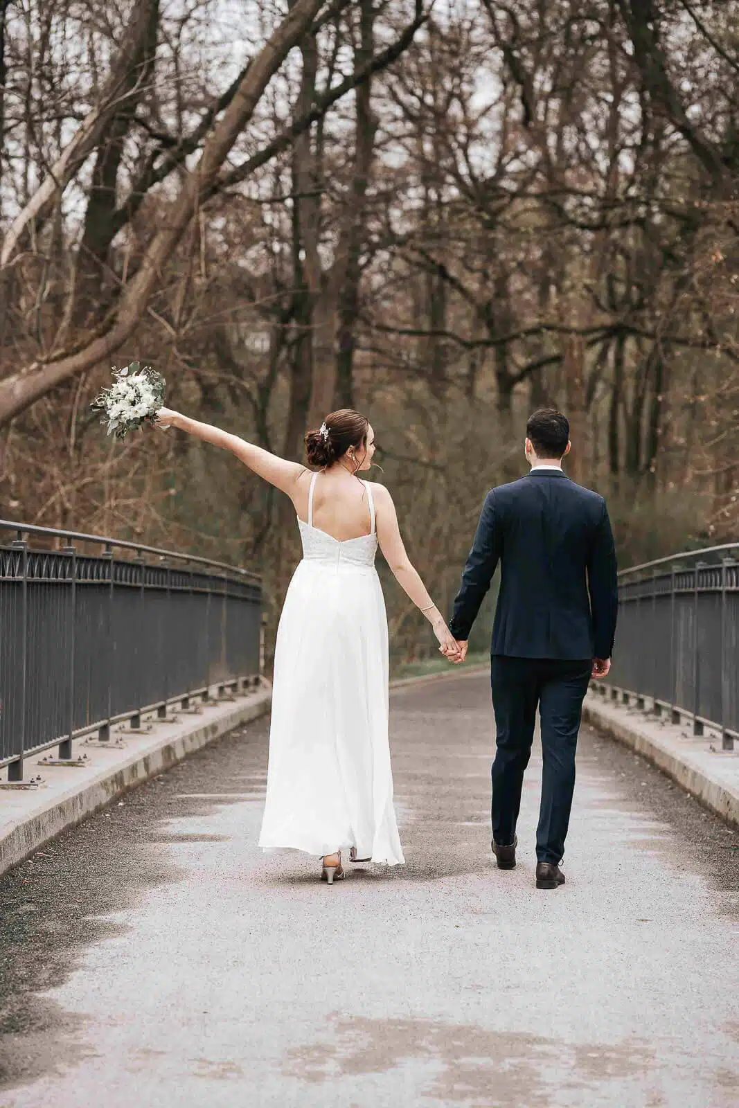 Hochzeitsfotograf Celle – Brautpaar auf Brücke mit erhobenem Brautstrauß und verliebten Blicken