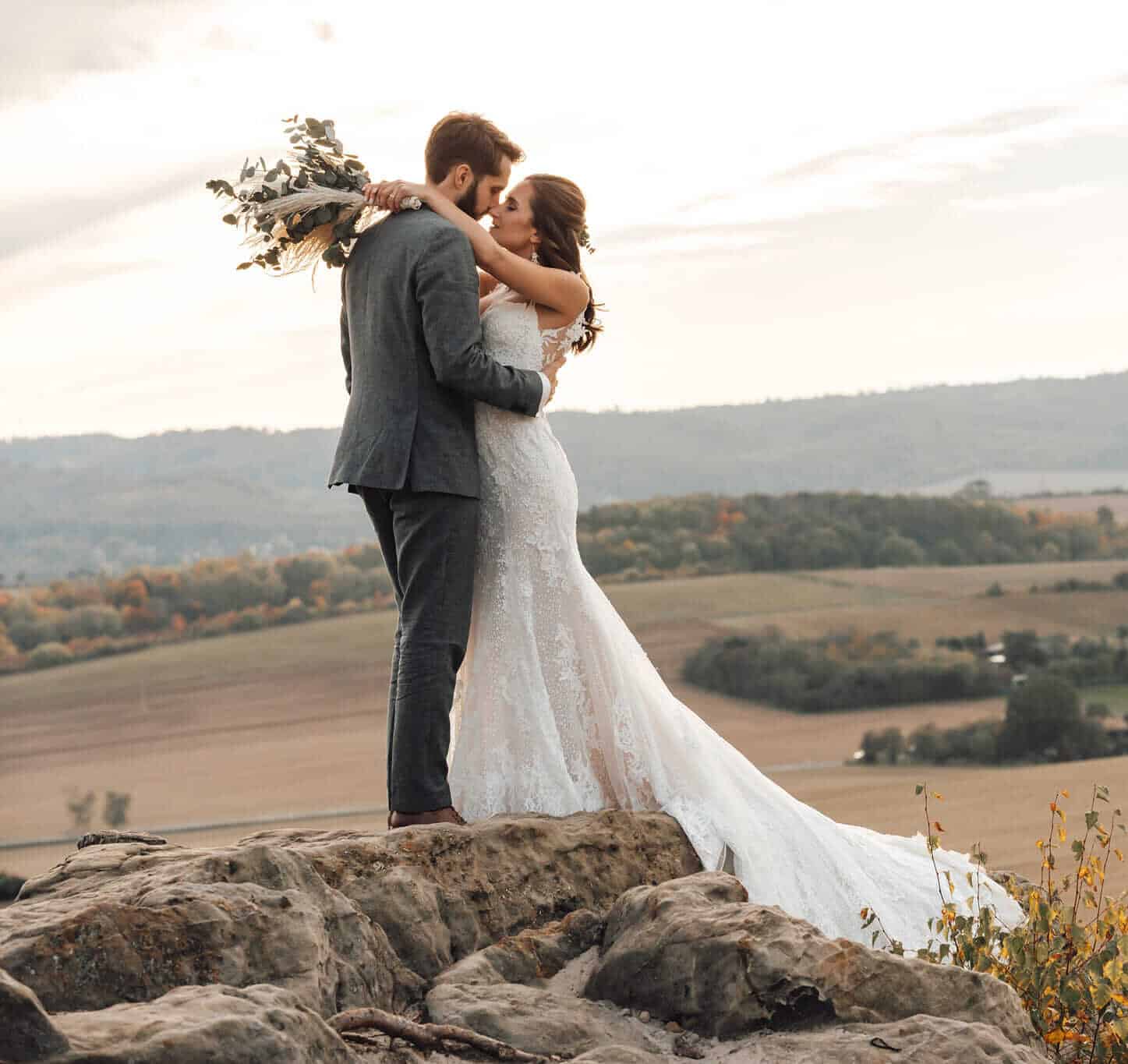 Brautpaar auf Felsen bei Sonnenuntergang in Braunschweig, emotionaler Blick und innige Umarmung