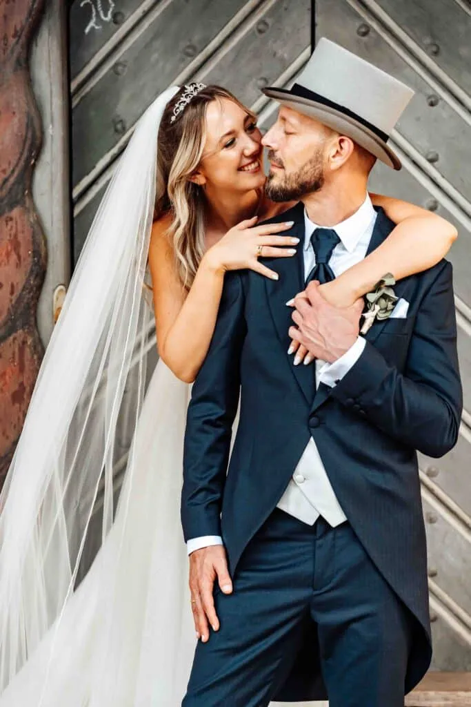 Braut mit langem Schleier und Bräutigam im Zylinder umarmen sich und schauen sich verliebt an – Hochzeitsfotograf Wolfsburg