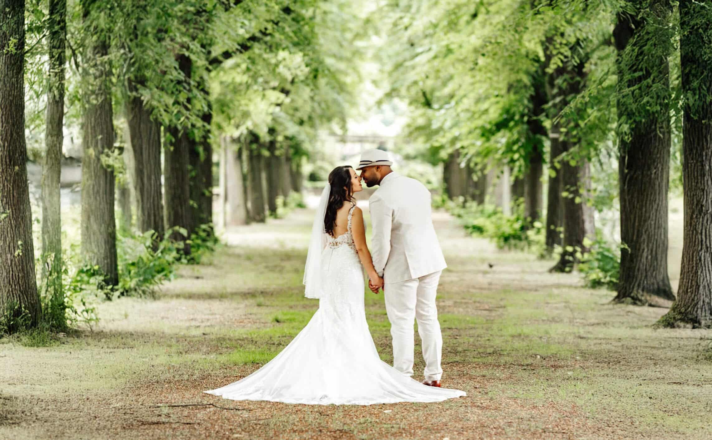 Braut und Bräutigam küssen sich im Park in Celle und halten sich liebevoll an den Händen